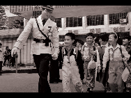 A policeman helps pupils of Shangbu Elementary School cross the road in 1995. [QQ.com]