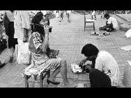 A women talks on a cell phone while having her shoes cleaned in Shenzhen in 1988. [QQ.com]