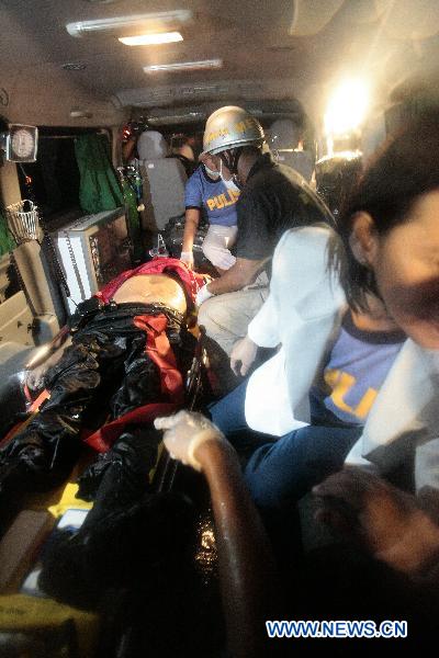 An injured victim is carried into an ambulance after a hostage-taker opened fired from inside a tourist bus full of Hong Kong tourists during a hostage crisis in Manila Aug. 23, 2010. [Rouelle Umali/Xinhua] 