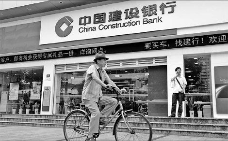 A man cycles past a branch of China Construction Bank Corp in Shanghai. [China Daily via agencies]