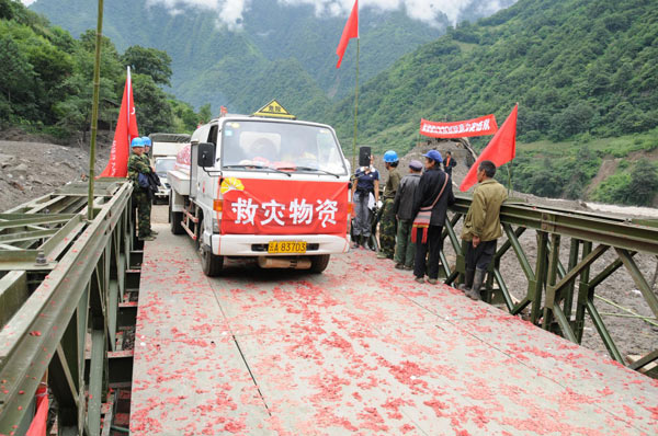 A truck carrying relief materials crosses a new bridge in Gongshan county, Southwest China&apos;s Yunnan province, Aug 24, 2010. [Xinhua]