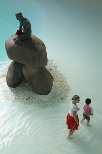 A boy prepares a birthday gift for the Little Mermaid, Aug 23, 2010. The Little Mermaid sculpture, one of Denmark&apos;s top tourist attractions, was brought to the Expo to strengthen ties between Denmark and China. It will return to Denmark after the Expo ends. [Xinhua]