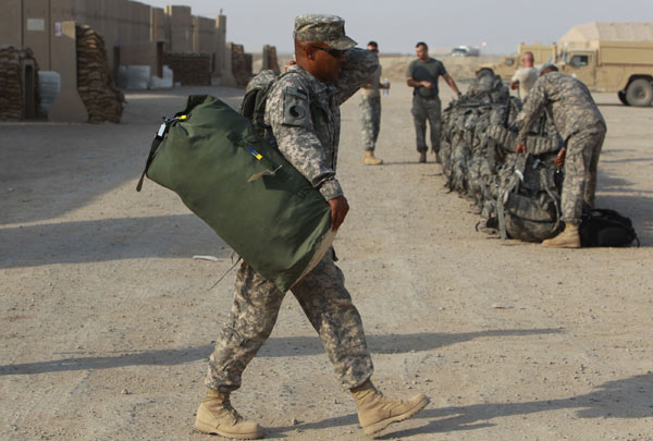 A U.S. soldier from the 1st Battalion, 116th Infantry Regiment, carries his bag to load into a vehicle as he prepares to leave Iraq for Kuwait, at Tallil Air Base near Nassiriya, 300 km southeast of Baghdad, August 15, 2010. [Xinhua]