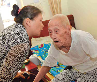Zhang Yuxia, who owns an elderly care home in Xiamen, Fujian province, talks to one of her residents. She believes quality of life is more important than being wealthy. [China Daily]