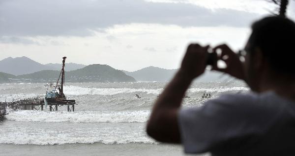 A tourist takes pictures of waves in Sanya, south China's Hainan Province, Aug. 24, 2010. High tides and big waves were seen on the sea water near Sanya due to a strong tropical storm named 'Mindulle' Tuesday.