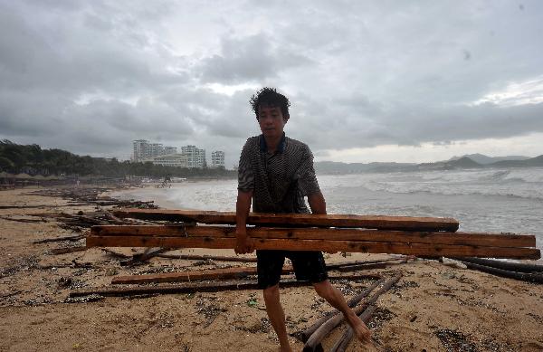 A man cleans the beach afer tides withdraw in Sanya, south China's Hainan Province, Aug. 24, 2010. High tides and big waves were seen on the sea water near Sanya due to a strong tropical storm named 'Mindulle' Tuesday.