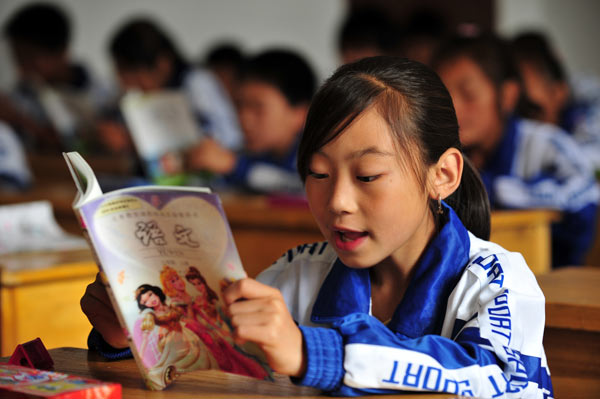 A girl reads from a textbook on the first day of the new semester at the No 2 Primary School in Zhouqu county, Northwest China&apos;s Gansu province, Aug 25, 2010. [Xinhua]