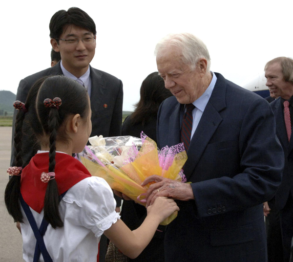 A DPRK girl presents flowers to visiting former US President Jimmy Carter at the airport in Pyongyang, Aug 25, 2010. [China Daily/Agencies]