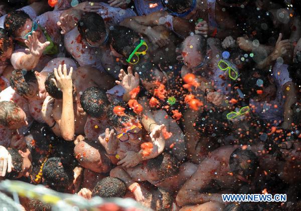 Revellers throw tomatoes to each other during the annual &apos;Tomatina&apos; (tomato fight) in the Mediterranean village of Bunol, near Valencia, Spain, on Aug. 25, 2010. About 40,000 revellers from around the world pelted each other with some 100 tonnes of ripe tomatoes Wednesday during the event in the eastern Spanish town of Bunol.[Xinhua]