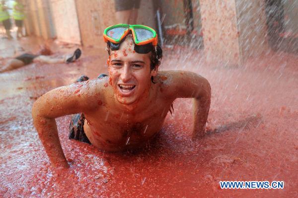  A reveller throws himself into tomato pulp during the annual &apos;Tomatina&apos; (tomato fight) in the Mediterranean village of Bunol, near Valencia, Spain, on Aug. 25, 2010. [Xinhua]