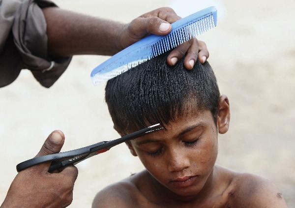 Amar Lal, 6, has his hair cut while taking refuge with his family at the Al Mujahid Army Relief Camp for flood victims in Sukkur, in Pakistan&apos;s Sindh province August 25, 2010.[Xinhua]