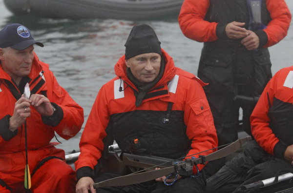 Russia&apos;s Prime Minister Vladimir Putin (C) holds a crossbow as he hunts for whales from a motorboat in Olga Bay in the Sea of Japan, August 25, 2010. Putin hit an endangered grey whale with the darts designed to take skin samples while participating in a whale research study with members of the Kronotsky Biosphere Reserve off Russia&apos;s Far Eastern coast on Wednesday, according to local media. [China Daily/Agencies] 