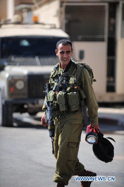 An armed Israeli soldier walks to his station in an Israeli military base near the Israel-Lebanon border, on Aug. 25, 2010.[Yin Dongxu/Xinhua]