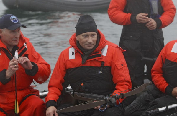 Russia's Prime Minister Vladimir Putin (C) holds a crossbow as he hunts for whales from a motorboat in Olga Bay in the Sea of Japan, August 25, 2010. Putin hit an endangered grey whale with the darts designed to take skin samples while participating in a whale research study with members of the Kronotsky Biosphere Reserve off Russia's Far Eastern coast on Wednesday, according to local media. 