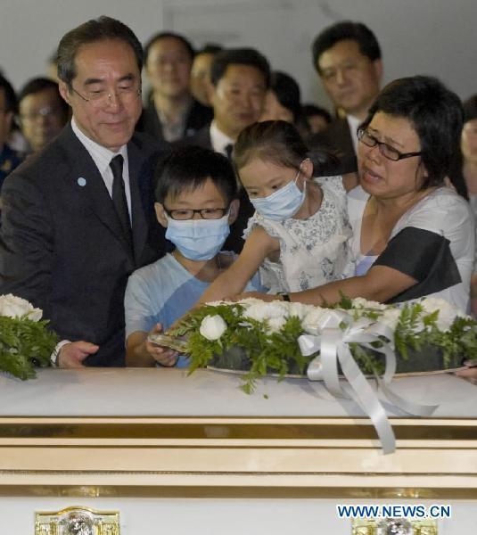 A girl poses a letter she wrote to her father on the coffin of her father in Hong Kong, south China, Aug. 25, 2010. The charter plane carrying tourist group members, victims' relatives and the bodies of the eight victims killed in Monday's hostage crisis in the Philippines arrived at Hong Kong Wednesday. 