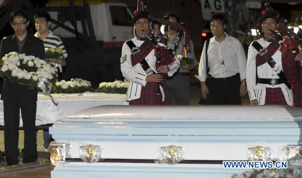 Bagpipers play the instruments during a ceremony to bid farewell to victims beside the coffins in Hong Kong, south China, Aug. 25, 2010. The charter plane carrying tourist group members, victims' relatives and the bodies of the eight victims killed in Monday's hostage crisis in the Philippines arrived at Hong Kong Wednesday.