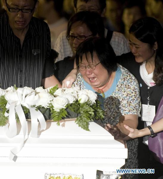 A victim's relative cry beside the coffin in Hong Kong, south China, Aug. 25, 2010. The charter plane carrying tourist group members, victims' relatives and the bodies of the eight victims killed in Monday's hostage crisis in the Philippines arrived at Hong Kong Wednesday. 