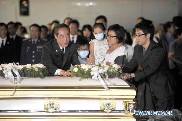 Henry Tang Ying-yen (L, front), the Chief Secretary for Administration of China's Hong Kong Special Administrative Region, poses flowers on a coffin of a victim in Hong Kong, south China, Aug. 25, 2010. The charter plane carrying tourist group members, victims' relatives and the bodies of the eight victims killed in Monday's hostage crisis in the Philippines arrived at Hong Kong Wednesday.