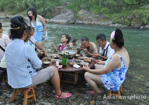 People have dinner in a village river in Kaili, Southwest China's Guizhou province on August 9, 2010. [Photo/China Daily viaAsianewsphoto]