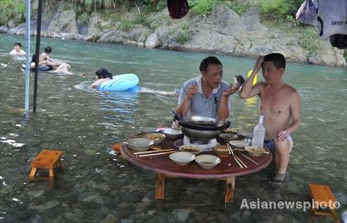 People have dinner and swim in a village river in Kaili, Southwest China's Guizhou province on August 9, 2010. [Photo/Asianewsphoto] 