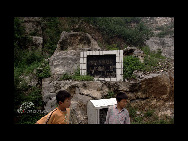 Two boys play in Huangtang. The stone tablet with the Chinese characters on it indicates a poverty-relief program for the village. [China.org.cn]