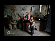 Yue Xiaoming plays in the kitchen at home in Yangquan village. [China.org.cn]