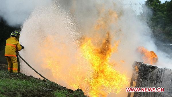 Firefighters try to put out the fire of a blasted oil tank on the highway in Guacara, Carabobo state of Venezuela, Aug. 26, 2010. The oil tank carrying 40,000 liters of gasoline blasted on the highway in Guacara left the driver injured and paralyzed the traffic for five hours. [Xinhua] 