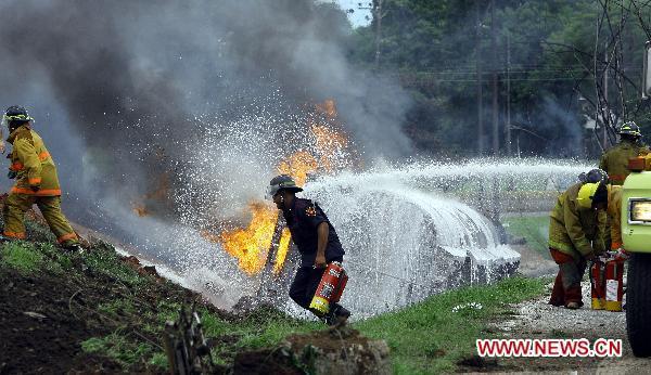 Firefighters try to put out the fire of a blasted oil tank on the highway in Guacara, Carabobo state of Venezuela, Aug. 26, 2010. [Xinhua] 