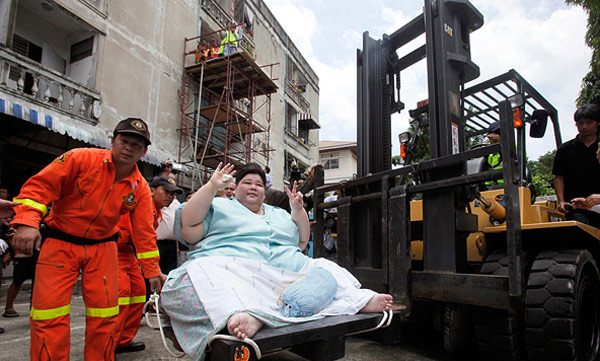 Umnuayporn Tongprapai gestures as she is transported on a forklift to an ambulance in Bangkok in this photo taken on Aug 26, 2010. The 274-kilogram woman believed to be the heaviest in Thailand left her apartment for the first time in three years Thursday with the help of Bangkok city hall and the forklift. [Chinanews.com]