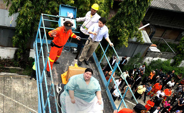 Umnuayporn Tongprapai sits on a trolley as she is removed from her third-floor apartment and transported to an ambulance, in Bangkok, Aug 26, 2010. [Chinanews.com]