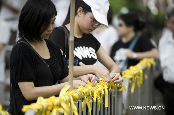 Girls tie yellow ribbons on a rail in the Chater Garden in Hong Kong, south China, Aug. 29, 2010. Around 80 thousand people took to streets to express their condolences to families of victims in the Manila&apos;s hostage tragedy and demand a thorough investigation on Monday&apos;s bloody hijack of a Hong Kong tour bus caused eight killed in Philippine&apos;s capital.[Xinhua]