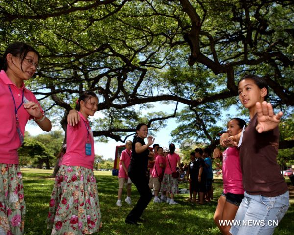 Hawaiian girls (Right Side) teach hula dance to Chinese girls and teachers of Shanghai Soong Ching Ling Foundation Children's Palace Art Troupe in Honolulu, Hawaii, the United States, Aug. 28, 2010. Forty-five students of the art troupe arrived in the resort on Aug. 24 to spend five days with their counterpart in Hawaii and to promote the Shanghai 2010 World Expo. 