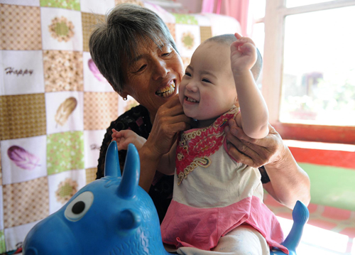 Jin Xianmei plays with her adopted child Dang Qingmi in Sancha village, Datong, Northwest China&apos;s Shanxi province, Aug 28, 2010. [Xinhua]