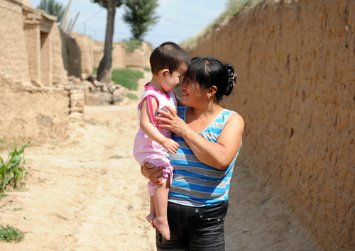 Yang Shuhua plays with her adopted child Dang Xiaole in Sancha village, Datong, Northwest China&apos;s Shanxi province, Aug 28, 2010. [Xinhua]