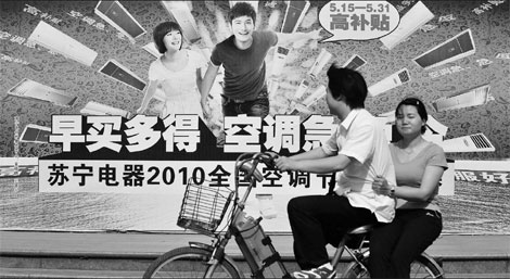 A couple passes a Suning Appliance advertisement in Nanjing. [China Daily]