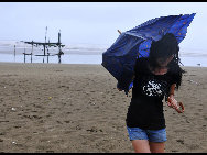 A woman struggles against the wind and rain in advance of tropical storm Namtheum on Tuesday in Shatian town in East China's Fujian province. [Xinhua]