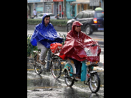 Two motorists are seen in rain in Hangzhou City, capital of east China's Zhejiang Province, Aug. 31, 2010. [Xinhua]