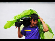 A cameraman is seen in the wind by sea in southeast China's Fujian Province, Aug. 31, 2010. [Xinhua]