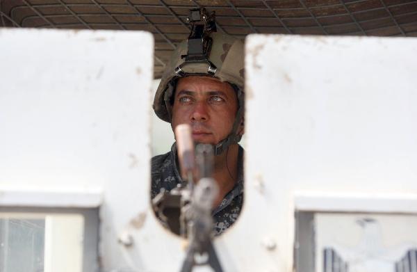 An Iraqi soldier secures the area from the top of an armored vehicle at a checkpoint in Baghdad on Aug. 31, 2010.[Xinhua/AFP]