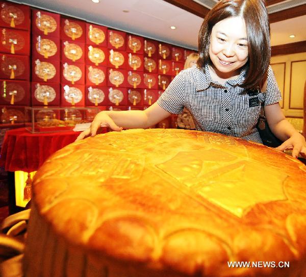 A citizen is attracted by a huge mooncake at Changchun Shangri-la Hotel, northeast China's Jilin Province, on Aug. 31, 2010. Mooncake manufacturers have waged wars on the market more than 20 days before the traditional Mid-Autumn Day. A mooncake tasting meeting was held at Changchun Shangri-la Hotel on Tuesday, attacting visitors from home and abroad to taste various curious mooncakes. [Wang Haofei/Xinhua]