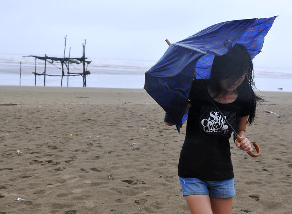 A woman struggles against the wind and rain in advance of tropical storm Namtheum on Tuesday in Shatian town in East China's Fujian province. [China Daily]