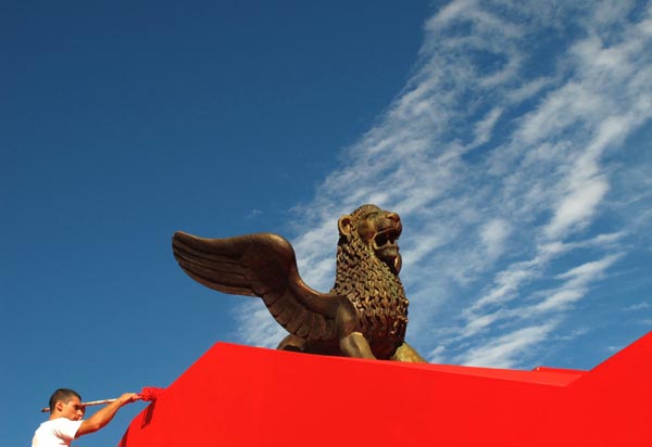 A worker paints a wall under a golden lion, a symbol of the Venice Film Festival, in front of the Cinema Palace in Venice August 30, 2010. The 67th Venice Film Festival will take place from September 1 to September 11, 2010.