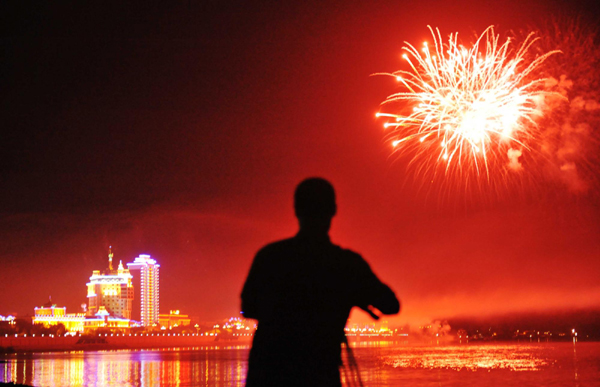 A photographer takes pictures of fireworks during a ceremony to commemorate the 65th anniversary of the end of World War II in Heihe, Northeast China&apos;s Heilongjiang province, Sept 2, 2010. [Xinhua]