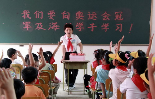 Deng Yaping,the former ping-pong champion, teaches English at the Huilei Primary School, specially for children of floating population, in Beijing on Sept 2, 2010. The floating population usually refers to migrant workers in China. Deng Yaping and several other former Olympic champions visited the school to cheer up children on their first day of the new semester. They also donated stationeries. [Xinhua]