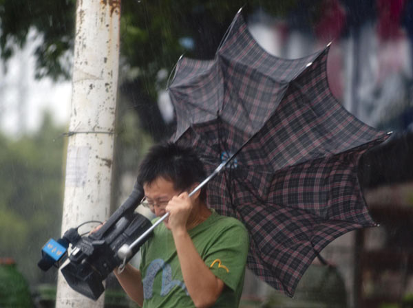 A cameraman&apos;s umbrella is blown off as he reports on the tropical storm Lionrock&apos;s landing in Zhangzhou city, Southeast China&apos;s Fujian province, Sept 2, 2010. [Xinhua]