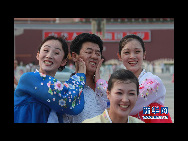 The DPRK performers from Pyongyang Art Troupe, dressed in traditional costumes, joke as they pose for a photo on the Tiananmen Square in Beijing during their touring trip to China, September 1, 2010. [Xinhua]