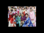 DPRK performers from Pyongyang Art Troupe, dressed in traditional costumes, with a staff member of Chinese performance company (C) pose for a photo on the Tiananmen Square in Beijing during their touring trip to China, September 1, 2010. [Xinhua]