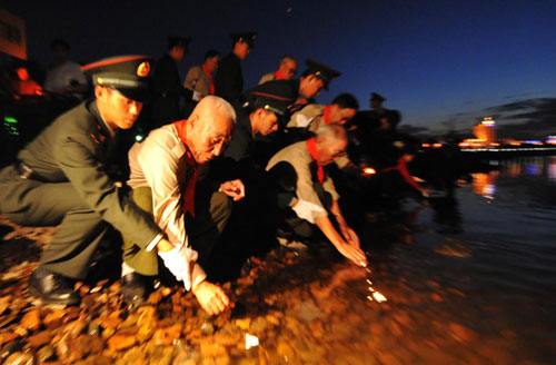 War veteran get help releasing candles into the Heilongjiang River to commemorate the 65th anniversary of the world anti-fascist war, in Heihe of Northeast China&apos;s Heilongjiang province Sept 2, 2010. The neighboring Blagoveshchensk city of Russia on the other side of the river simultaneously set off fireworks to mark the day. [China Daily/Agencies]