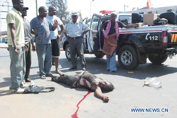 People stand beside the body of a person killed in the riot in Maputo, capital of Mozambique, Sept. 1, 2010. [Xinhua]