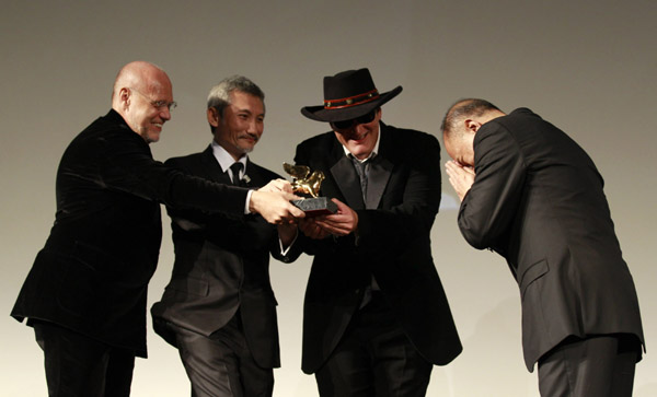 Director John Woo (R) reacts as he receives a Golden Lion for Lifetime Achievement from Directors Marco Muller (L), Quentin Tarantino (2 to R) and Tsui Hark during the closing ceremony of the 66th Venice Film Festival September 3, 2010. [Xinhua]